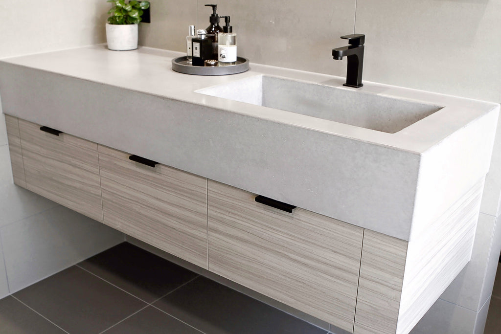 Custom concrete vanity top by DLH Designs with an integrated rectangular basin in grey