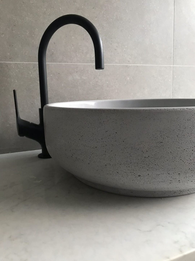 Lauren Round Concrete Basin by DLH Designs in a neutral bathroom with a black mixer tap